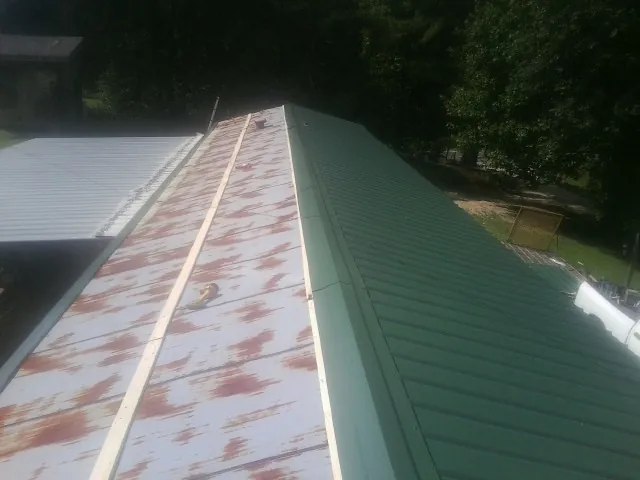 Old rusted panels beside newly installed green metal roofing — Wind Damage Roof Repair by Roofing Brothers in Placitas