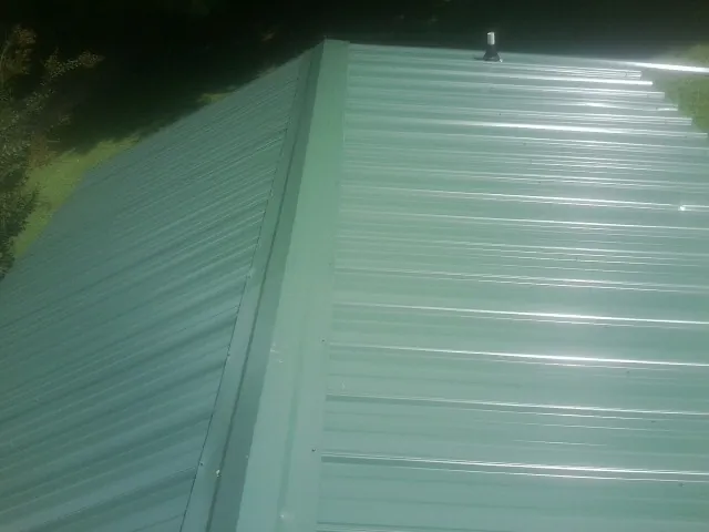 New green metal panels meeting at the ridge of a roof — Flat Roof Repair work by our crew in Placitas