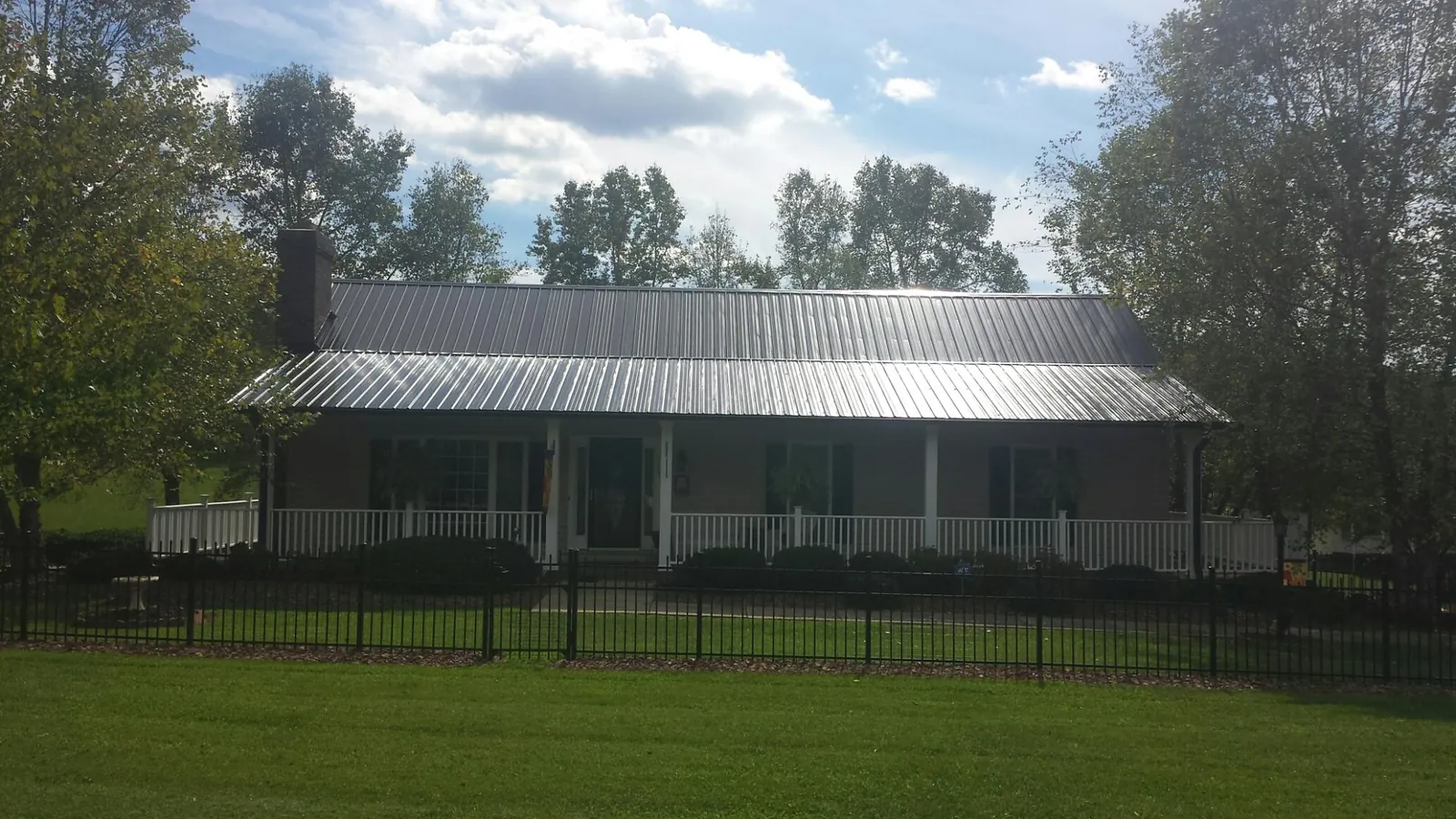 Gray metal roof on a brick ranch with a full width front porch — Gutter Guard Installation work by our crew in Placitas