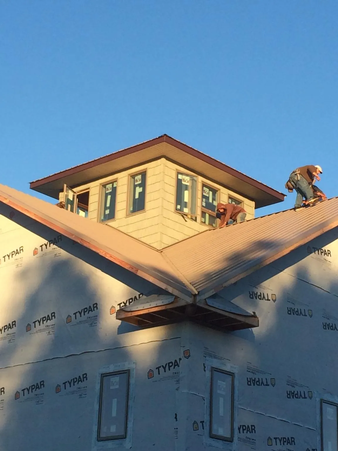 Roofers working around a rooftop cupola on a new metal roof at sunset — Roof Waterproofing in Placitas by Roofing Brothers